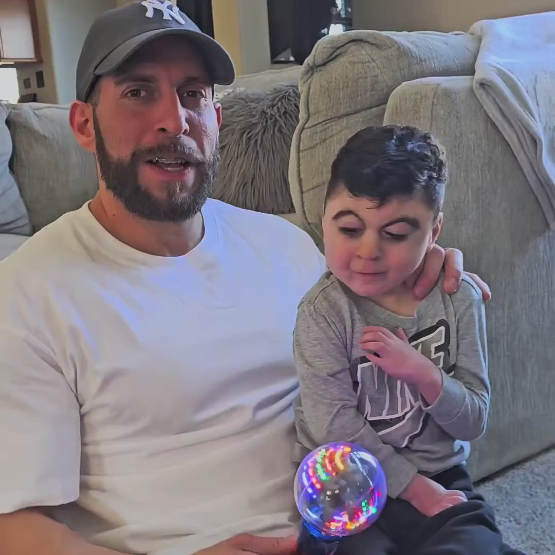 A parent and child explore the Mimsy Glow & Spin Sensory Wand's colorful light patterns.