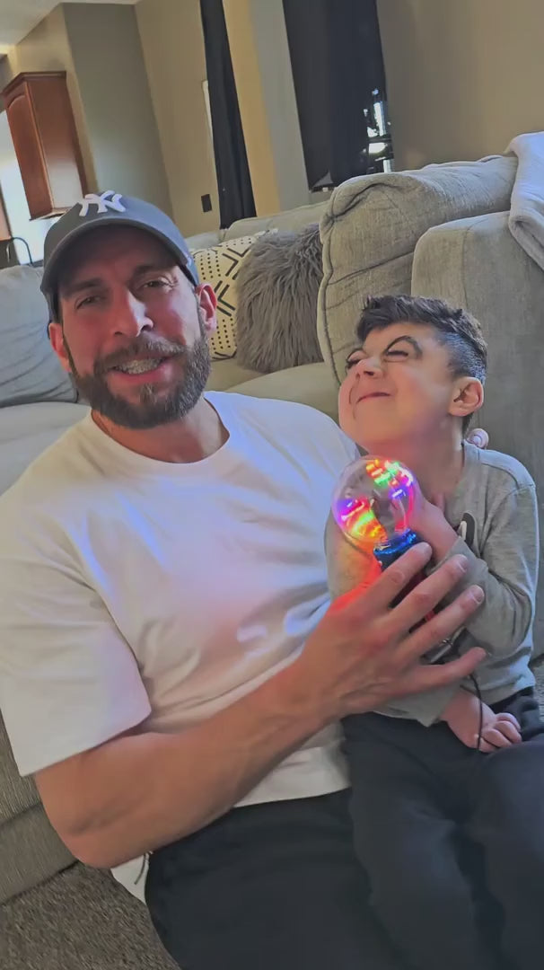A parent and child demonstrate the Mimsy Glow & Spin Sensory Wand.